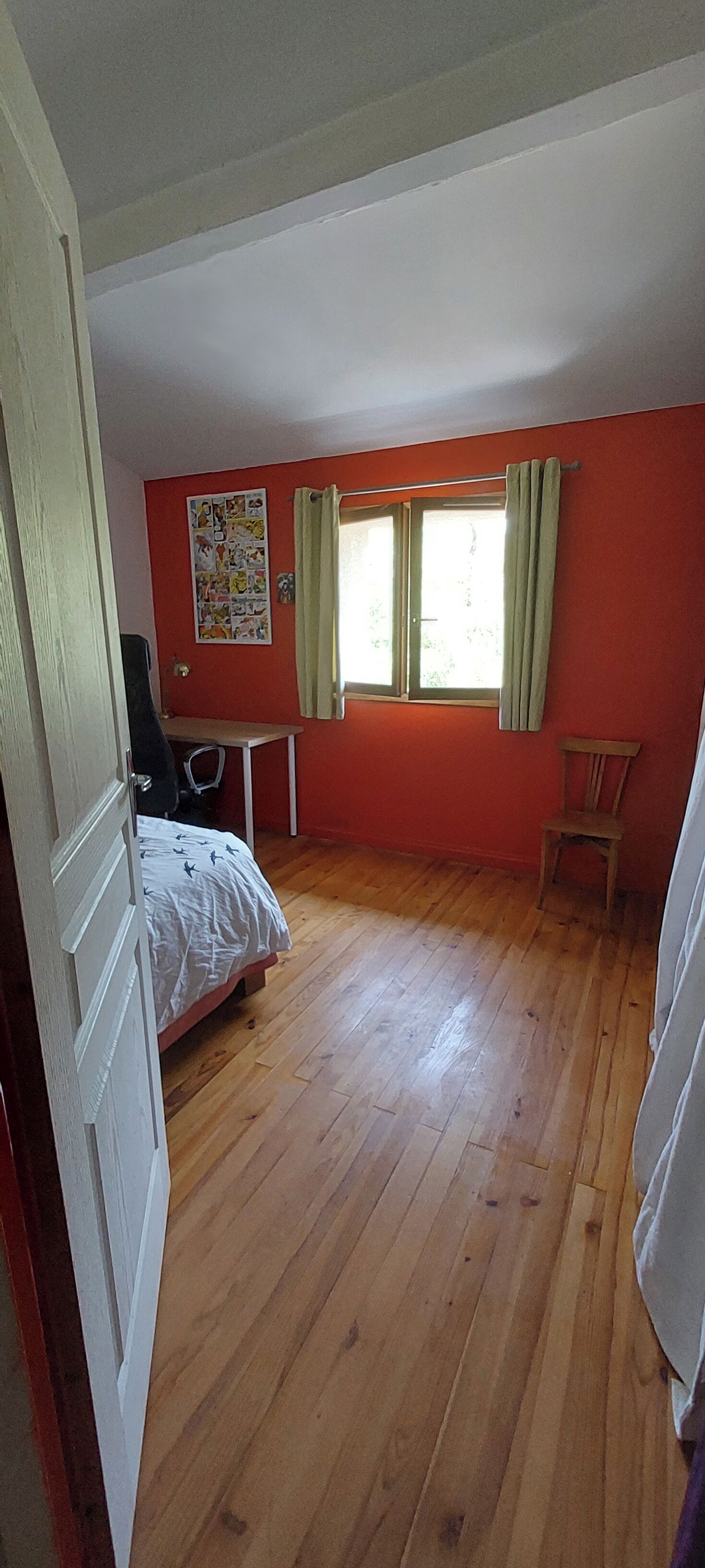 A room with a bed, a desk, a chair, and a window with curtains.