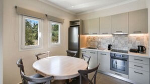 A modern kitchen with a dining area, featuring a large round table, chairs, a refrigerator, an oven, and a sink. - Lainas Sea View Lefkada (Lefkada)