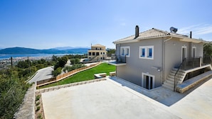 A two-story house with a balcony, a driveway, and a view of the sea and mountains. - Lainas Sea View Lefkada (Lefkada)