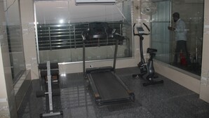 A gym with a treadmill, elliptical, and weight machine.