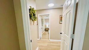 A hallway with wooden flooring, beige walls, and white doors.