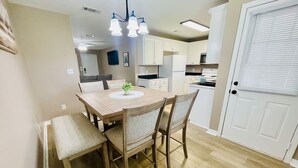 A dining area with a wooden table and chairs, a bench, and a hanging light fixture.