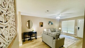 A living room with a sofa, a desk, and a decorative wall panel.