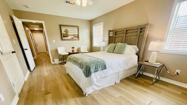 A bedroom with a large bed, a bedside table, a lamp, and a window.