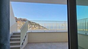 A balcony with a metal railing overlooking a cityscape with buildings and a hill. - Residenza Albachiara (Castelsardo)
