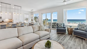 Un salon moderne avec un grand canapé, une table basse et une vue sur l’océan.