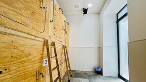 A room with wooden cabinets numbered 1 to 5, a ladder, and a window with a view. - Cubik Rooms (Madrid)