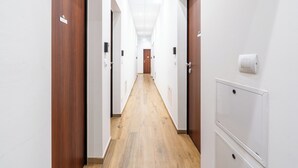 A long, narrow hallway with wooden doors on either side and a white wall on the right. - Hotiday Torino OGR (Turin)