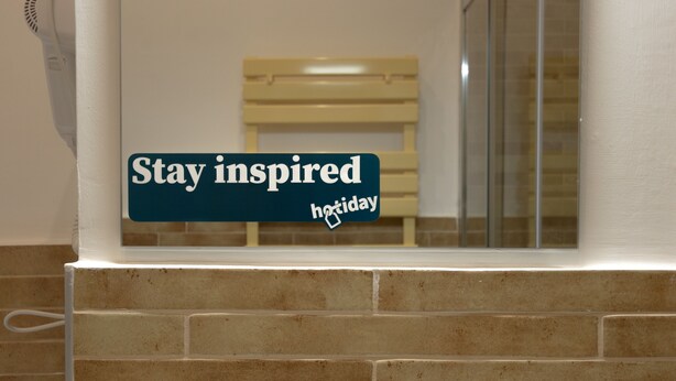 A sign with the text "Stay inspired" and "holiday" in a hotel setting. - Hotiday Torino OGR (Turin)