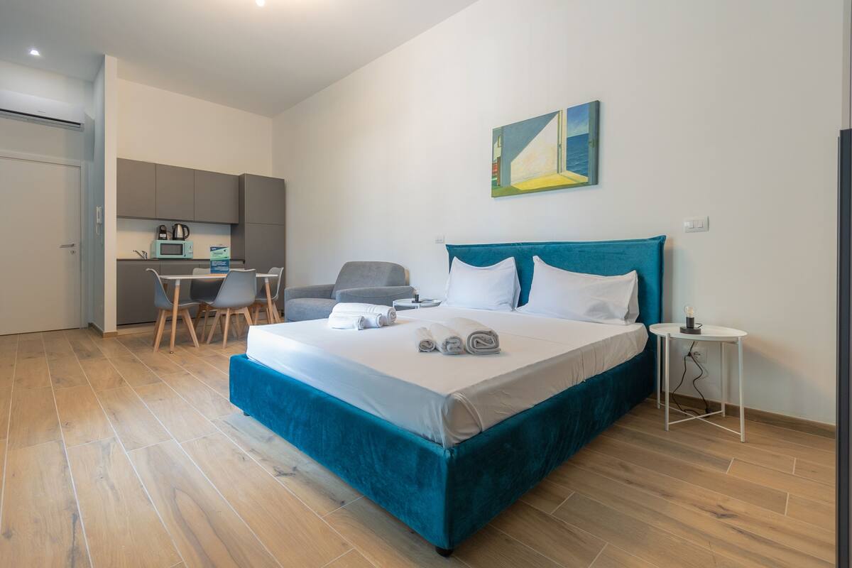 A bedroom with a large bed, a desk, and a chair.