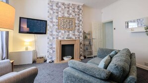 Una sala de estar con chimenea, televisor y sofá.