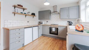 A modern kitchen with grey cabinets, a wooden countertop, and a tiled backsplash. - Fabulous 3 bedroom Home in Redcar (Redcar)