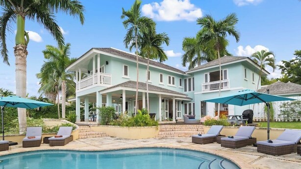 A large house with a swimming pool, lounge chairs, and palm trees. - Greens All (Montego Bay)