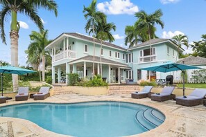 A large house with a swimming pool, lounge chairs, and palm trees. - Greens All (Montego Bay)