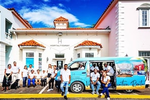 A group of people standing in front of a building with a sign that reads "HOSPITALITY EXPERT."