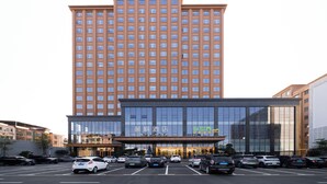A multi-story hotel with a modern facade, a parking lot in front, and several cars parked. - Lavande Hotel Dongguan Shipai  (Dongguan)