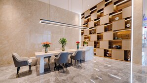 A modern dining area with a marble floor, a long table with four chairs, and a decorative wall with shelves. - Lavande Hotel Dongguan Shipai  (Dongguan)