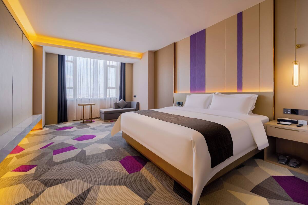 Ein Hotelzimmer mit einem großen Bett, einem Nachttisch und einer kleinen Sitzecke.