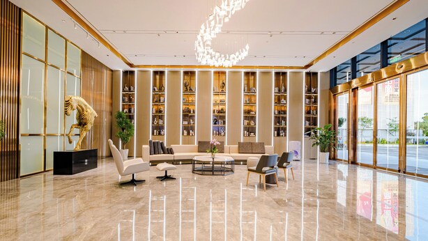 A modern lobby with a marble floor, a central seating area with sofas and chairs, tall bookshelves, and a decorative sculpture. - Lavande Hotel Dongguan Shipai  (Dongguan)