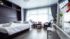 A modern hotel room with a large bed, a small table with chairs, a TV, and a window with curtains. - Awenasa by Livinginn (Ho Chi Minh City)