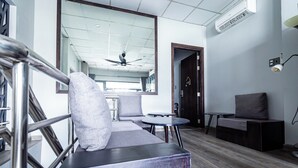 A modern hotel lobby with a staircase, seating area, and a large mirror reflecting the ceiling and a ceiling fan. - Awenasa by Livinginn (Ho Chi Minh City)