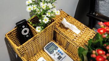 A wicker basket containing a remote control, a white device, and a tissue.
