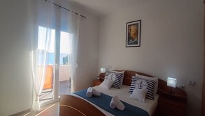 Ein Schlafzimmer mit einem Bett, zwei Nachttischen, einem Fenster mit Vorhängen und einem Bild an der Wand.
