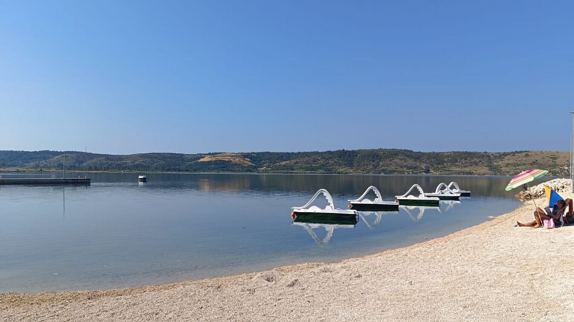 Un lac paisible où plusieurs pédalos sont amarrés près du rivage.