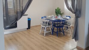 Ein Essbereich mit einem runden Tisch, blauen Stühlen und einer Topfpflanze.