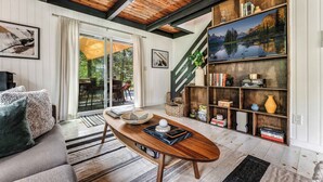 Ein modernes Wohnzimmer mit Holzboden, einer Couch, einem Couchtisch und einem Bücherregal.