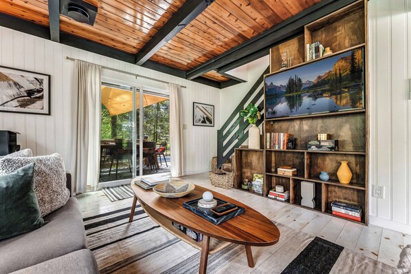 Un salon moderne avec un plafond en bois, un canapé, une table basse et une bibliothèque.