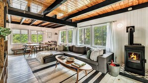 Ein gemütliches Wohnzimmer mit Kamin, einer Couch, einem Couchtisch und einem Essbereich mit einer Bank.