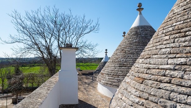 A stone-roofed building with a white chimney and a view of a green landscape.