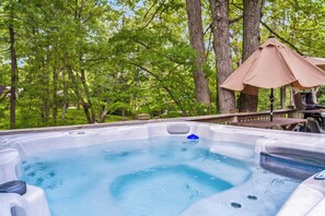 Ein Whirlpool, umgeben von Bäumen und einer Holzterrasse.