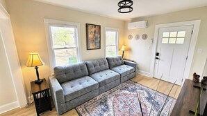 A living room with a grey sofa, two lamps, a patterned rug, and a door with a window.