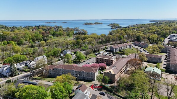 An aerial view of a residential area with houses, a parking lot, and a body of water in the background. - Tranquil modern upstairs apt. Walk to restaurants & beach! Off-street parking, (Greenwich)