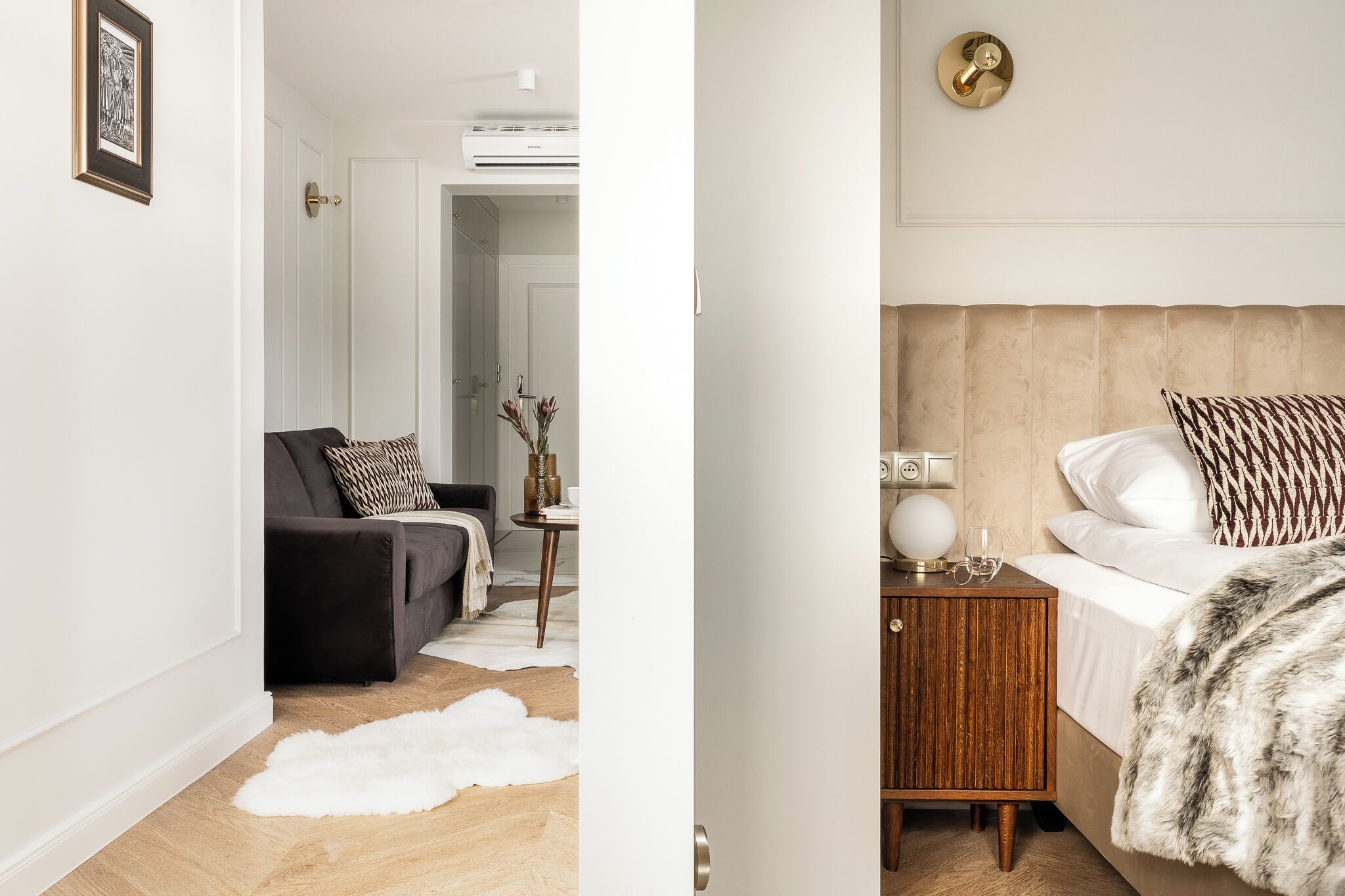 A modern bedroom with a bed, a nightstand, a sofa, and a small table with decorative items.