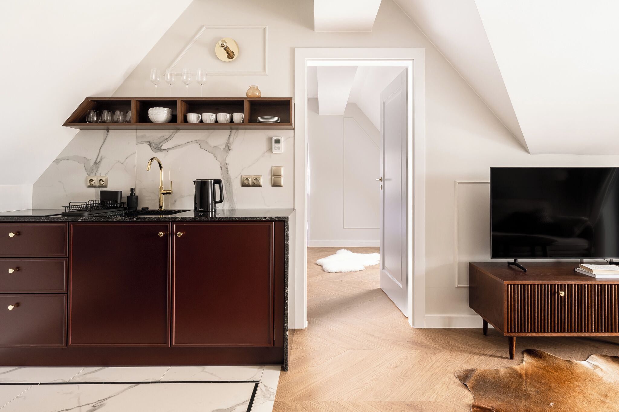 A modern kitchen with dark wood cabinets, a marble backsplash, and a built-in stove.