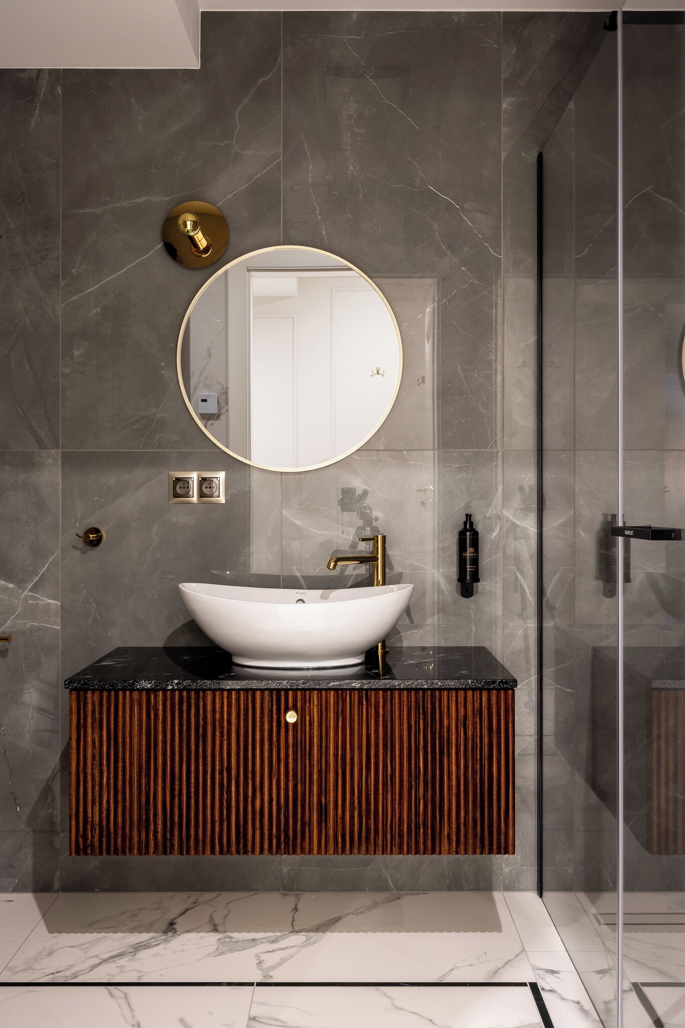 A modern bathroom with a large oval mirror, a white vessel sink, and a wooden vanity.