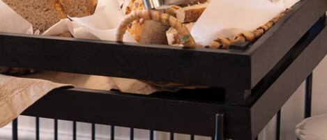 A buffet setup with various breads and rolls.