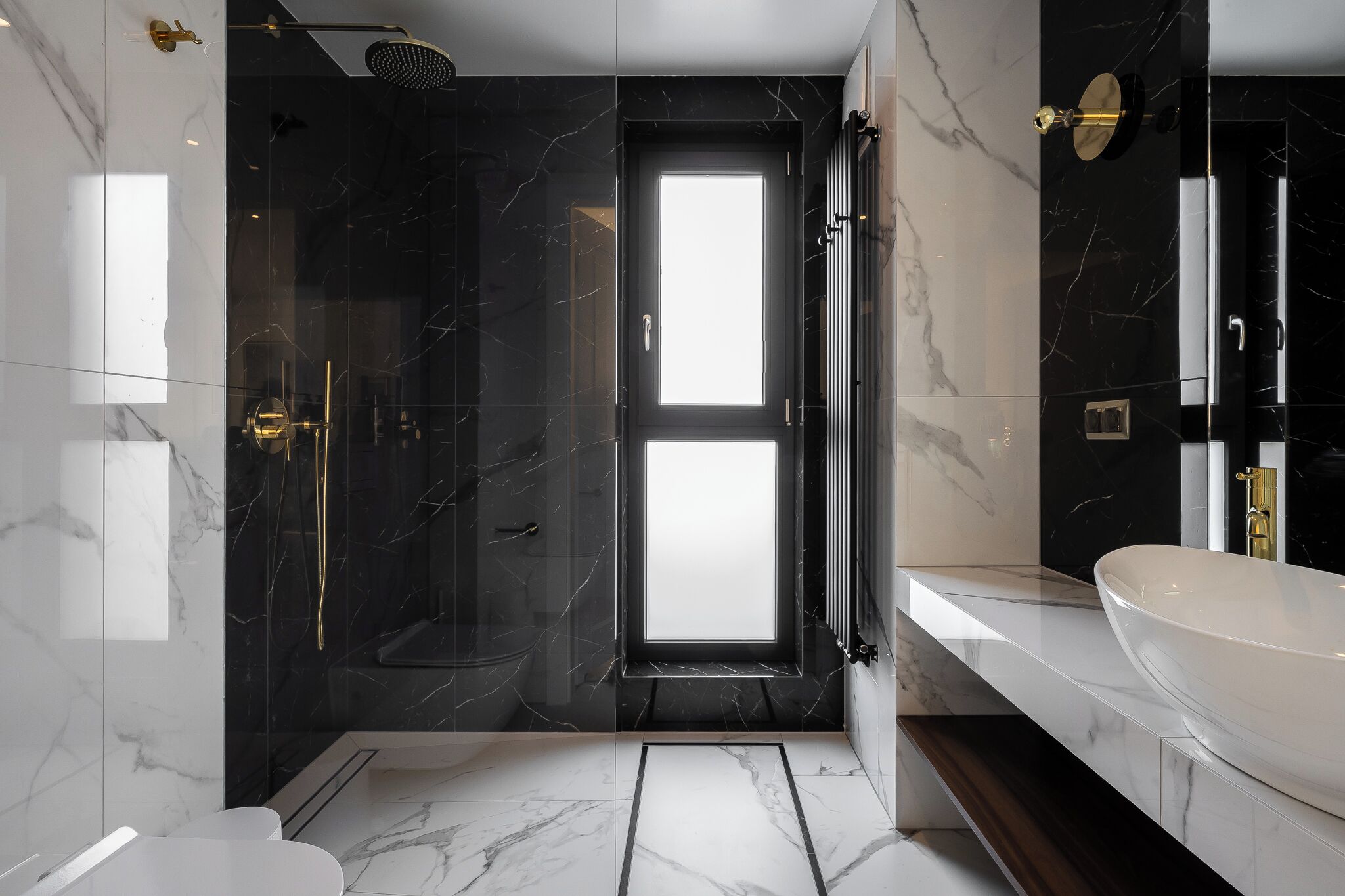 A modern bathroom with a large mirror, a white sink, and a glass-enclosed shower.