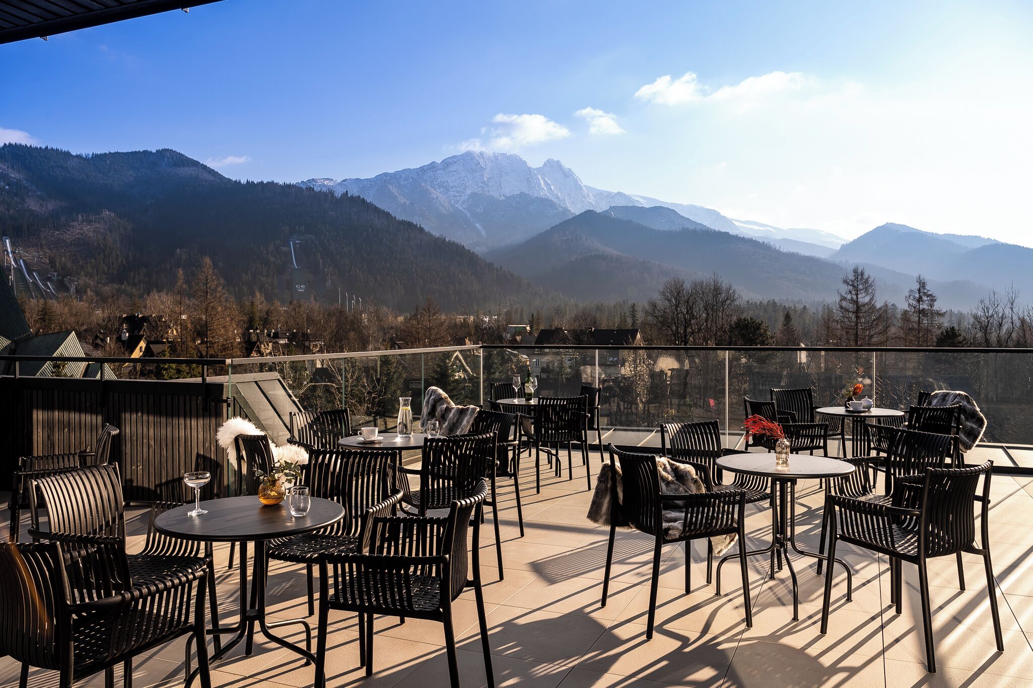 Una terraza al aire libre con mesas y sillas, con vistas a un paisaje montañoso.