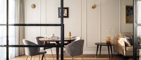 Una sala moderna con una mesa redonda de comedor, sillas tapizadas en gris, un sofá color beige y una mesa de centro de vidrio.