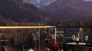 A terrace with round tables and chairs, a bottle of wine, and a teapot.