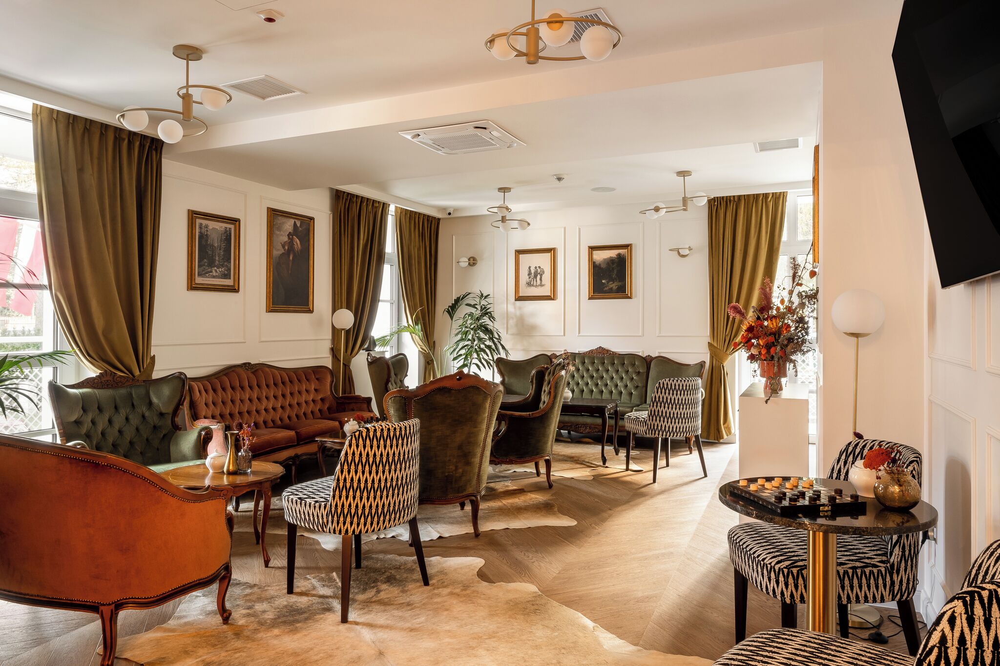 A spacious living room with a large sofa, multiple armchairs, a coffee table, and a television.