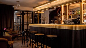 A bar area with a wooden counter, stools, and a variety of bottles and glasses. - Renesans Residence Zakopane (Zakopane)