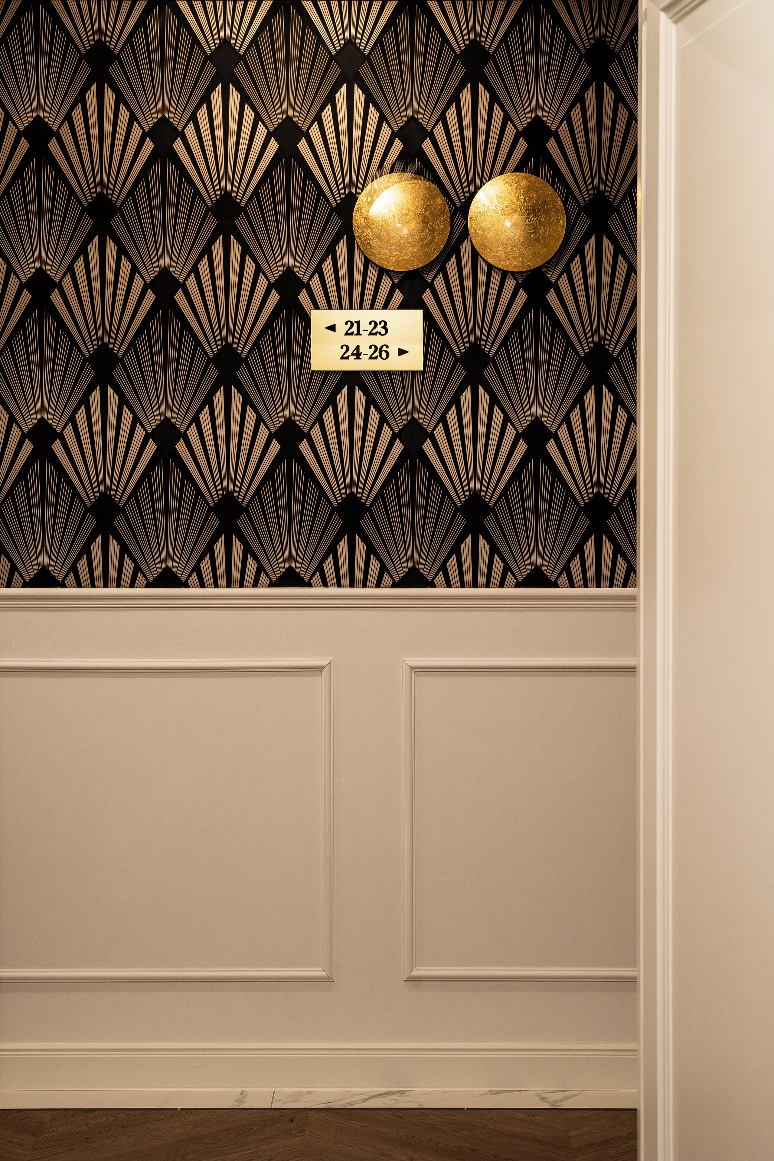 A wall with a geometric pattern and two gold spherical light fixtures.
