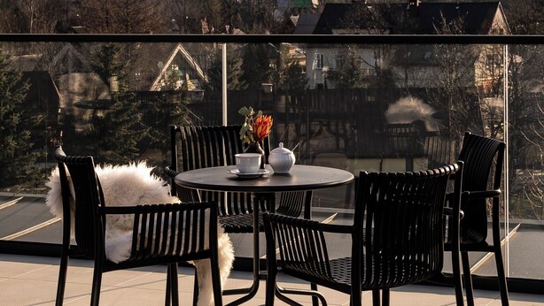 A terrace with a round table and chairs, overlooking a mountainous landscape. - Renesans Residence Zakopane (Zakopane)