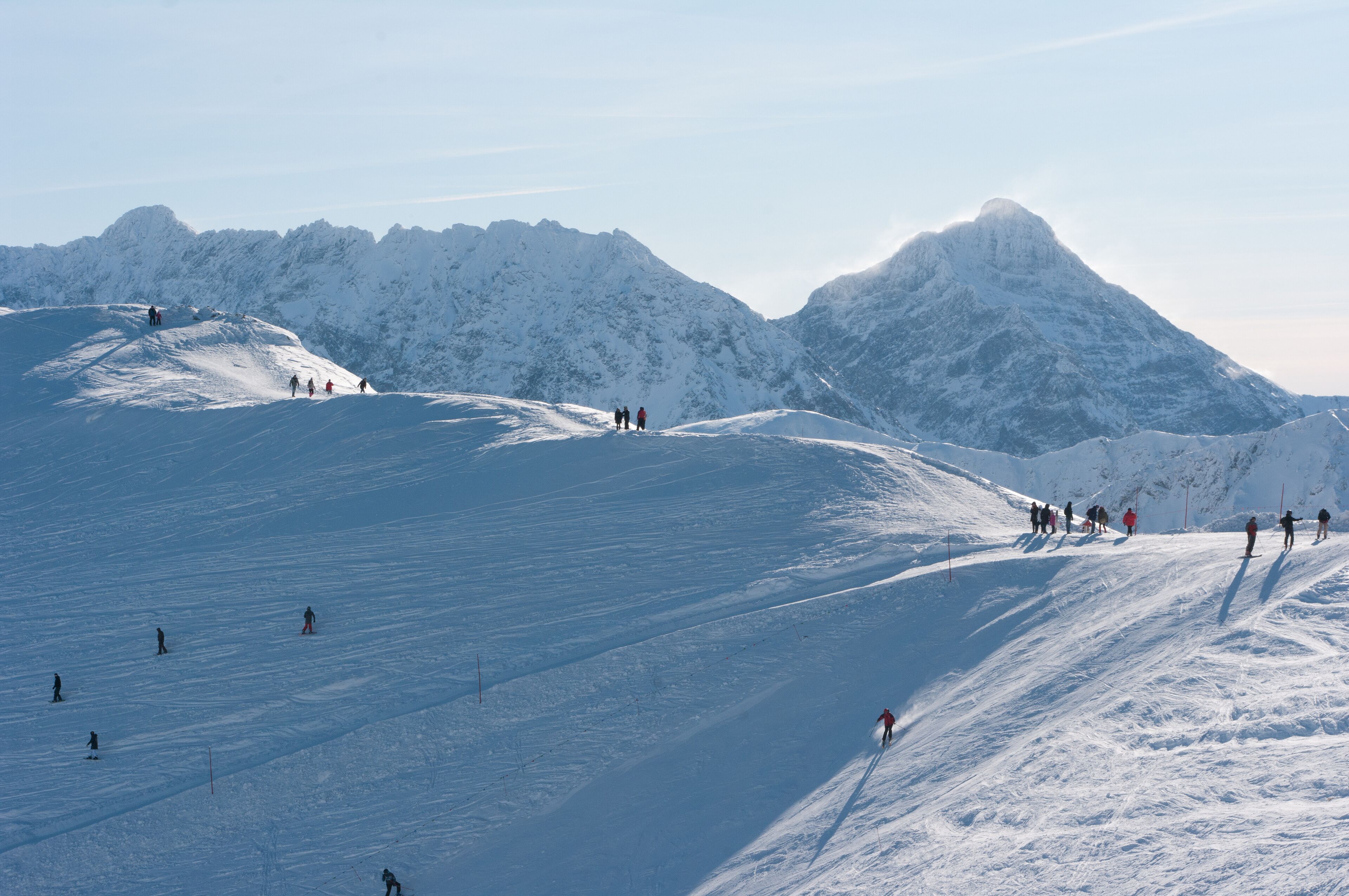 A snow-covered mountain slope with skiers and snowboarders.