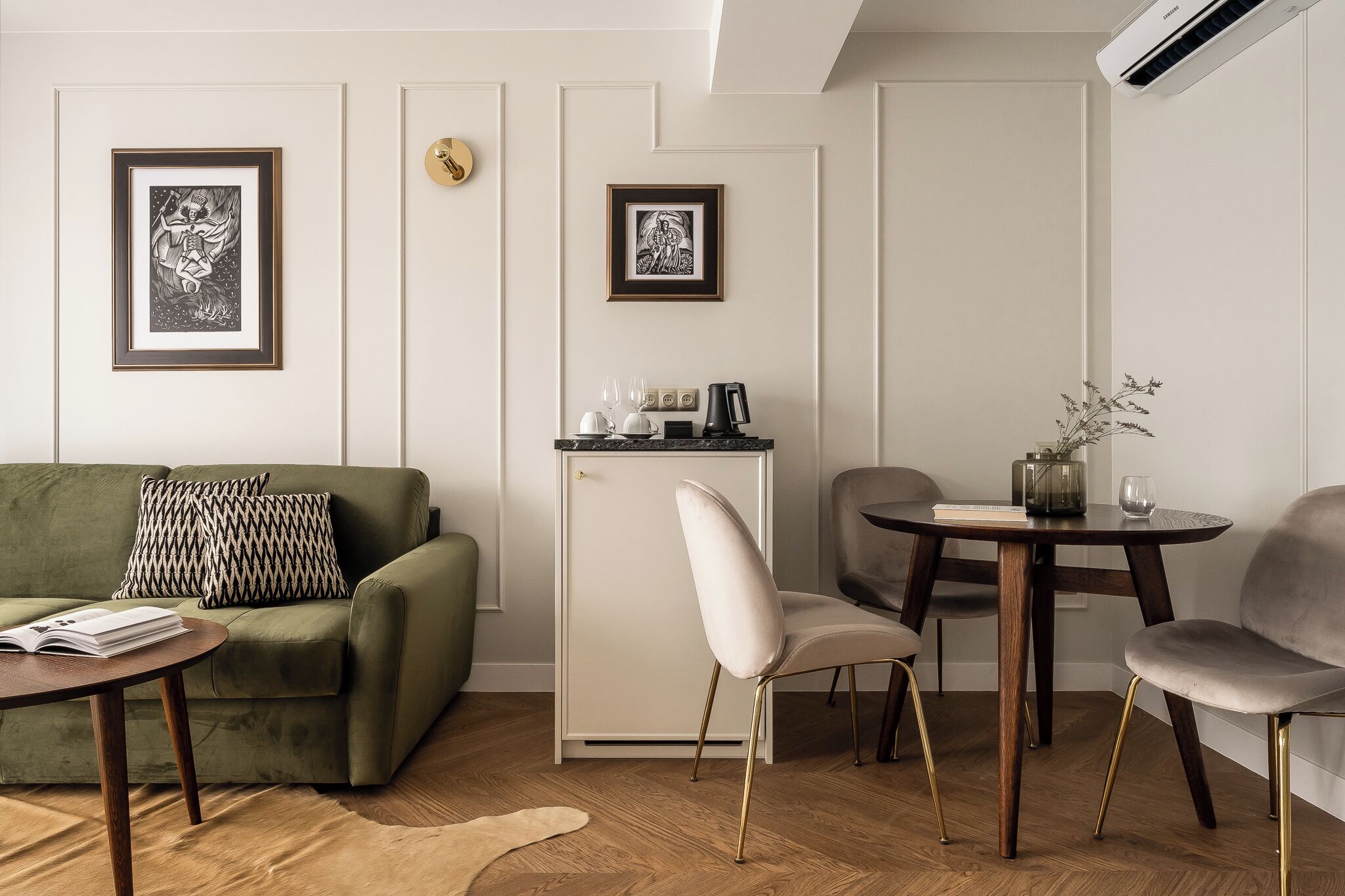 A modern living room with a green sofa, a white cabinet, and a round table with chairs.